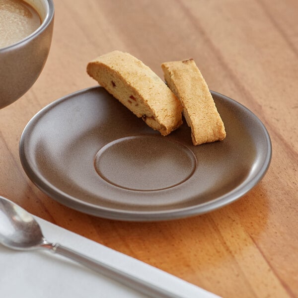 A plate with food next to a cup of coffee on a saucer.