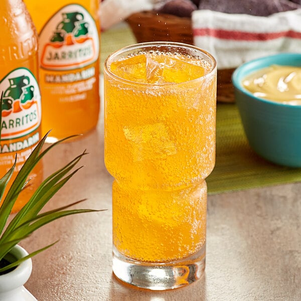 A close-up of a glass of Jarritos Mandarin Soda with ice.