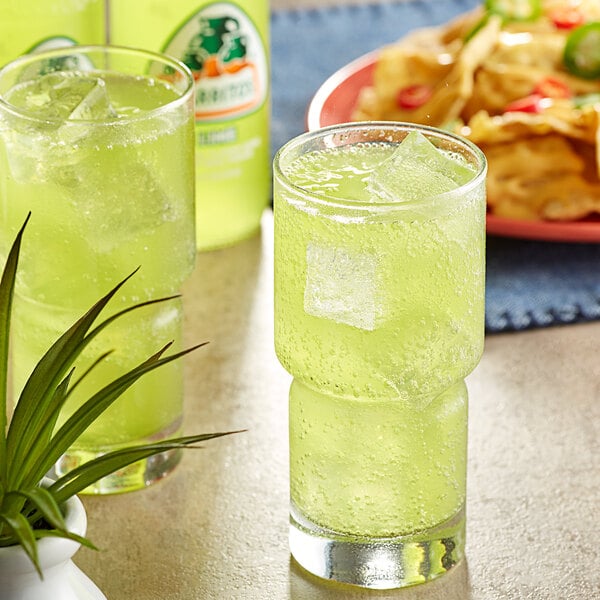 A close-up of a glass of Jarritos Lime soda with ice.