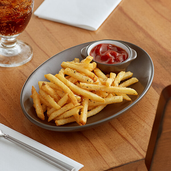 An Acopa hickory brown matte coupe stoneware platter with french fries, ketchup, and a glass of soda on a wood table.