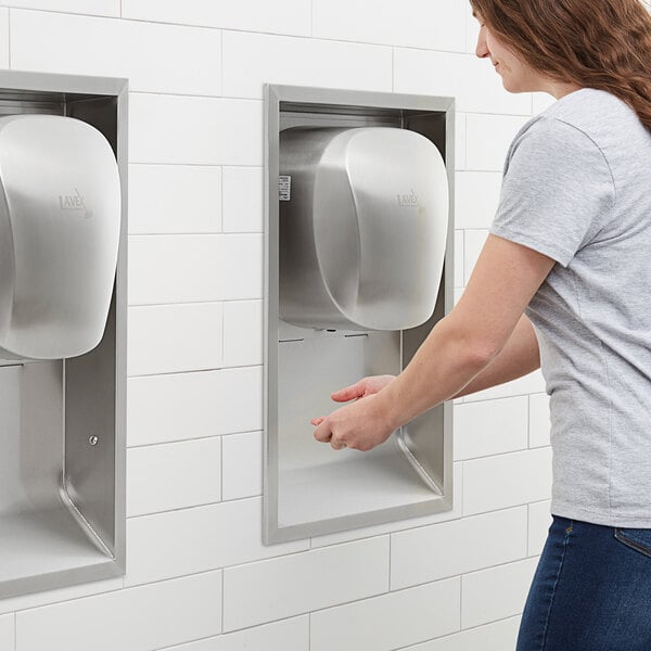 A woman using a Lavex stainless steel automatic hand dryer.