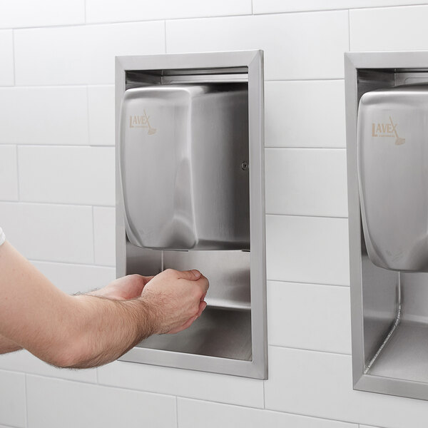 A man using a Lavex Stainless Steel automatic hand dryer in a public restroom.