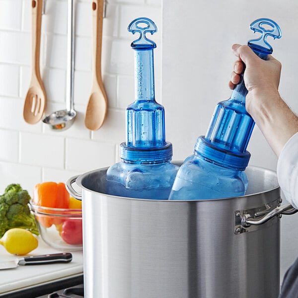 A person using two blue San Jamar Rapi-Kool bottles to cool food in a large pot.