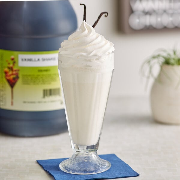 A bottle of I. Rice Vanilla Milkshake Base Syrup with a glass of white liquid and a straw.