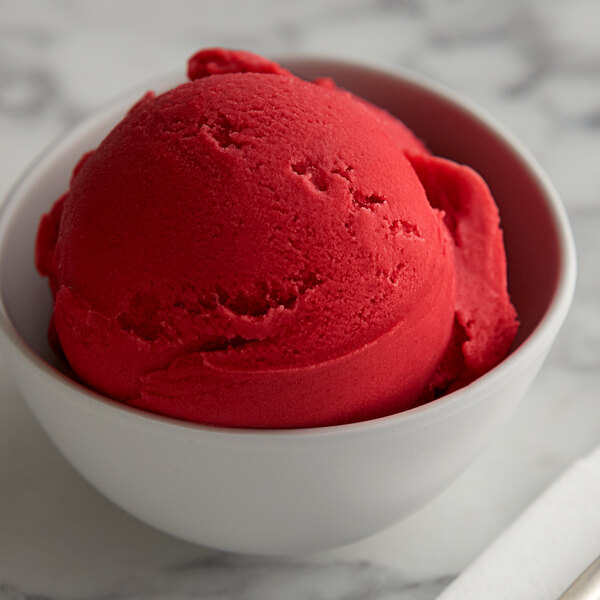 A bowl of red Raspberry Italian ice with a scoop of ice cream on top.