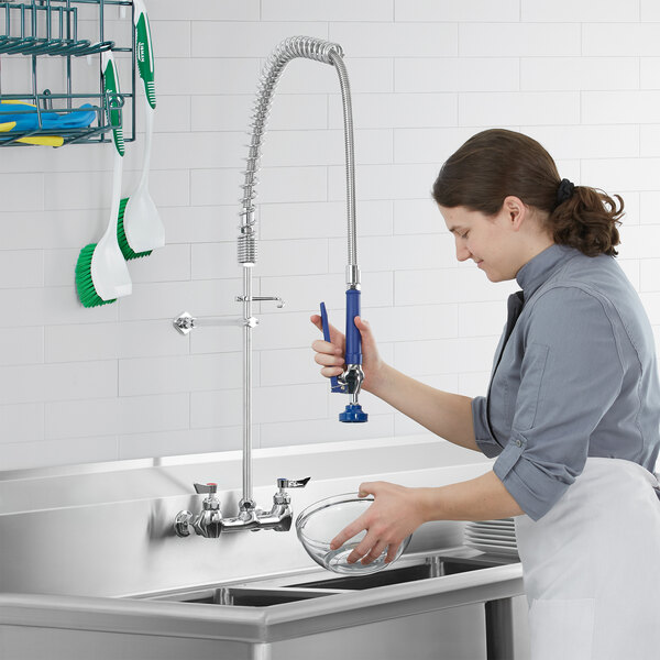 A woman using a Waterloo pre-rinse faucet to wash dishes in a sink.