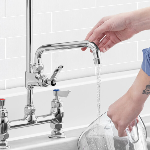 A person using a Waterloo pre-rinse add-on faucet to pour water into a sink.