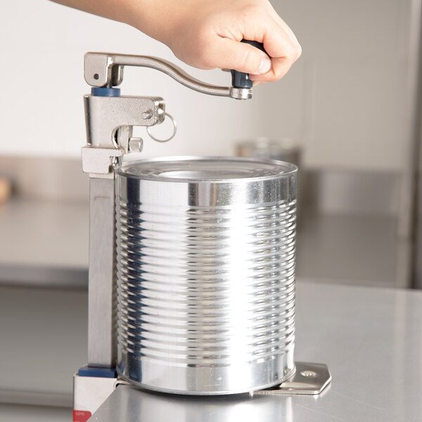 A person using an Edlund Standard Duty Manual Can Opener to open a can on a counter.