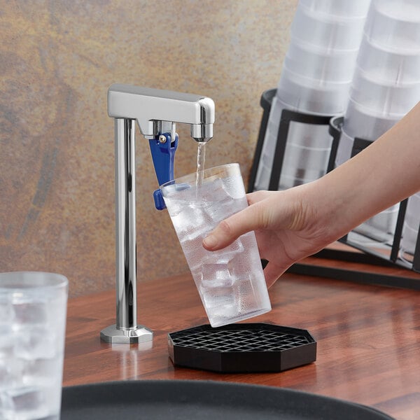 A hand using a Waterloo countertop glass filler to fill a glass with ice.
