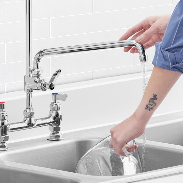 A person washing their hands in a sink with a Waterloo pre-rinse add-on faucet.