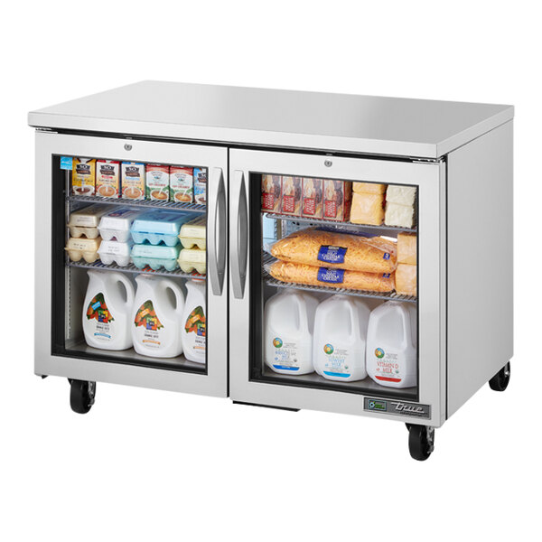 A True undercounter refrigerator with glass doors and shelves.