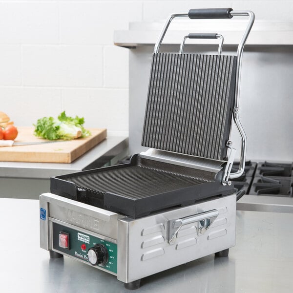 A Waring Panini Perfetto sandwich grill machine with a grooved griddle on the top.