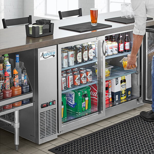 An Avantco back bar refrigerator full of drinks on a counter in a bar.