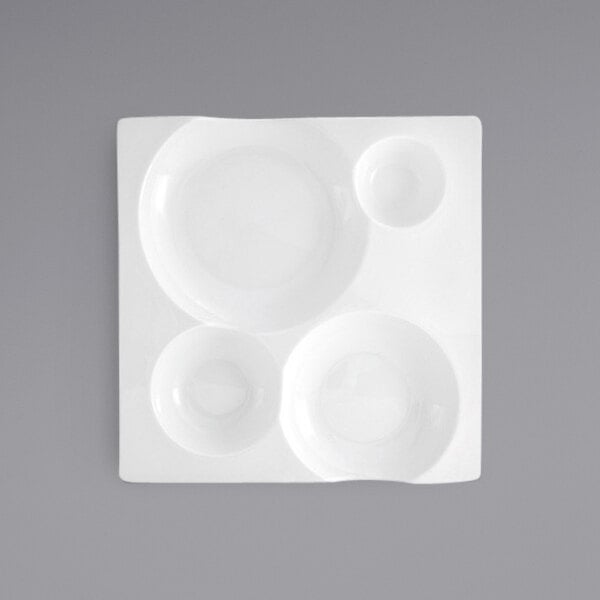A close up of a white Front of the House Harmony 4-compartment porcelain plate.