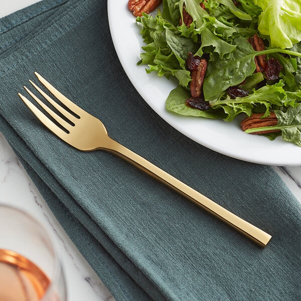 An Acopa Phoenix stainless steel forged salad fork on a plate of salad.