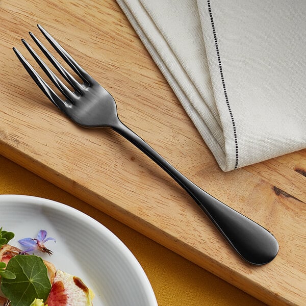 An Acopa Vernon stainless steel salad fork with a piece of food on it on a table.