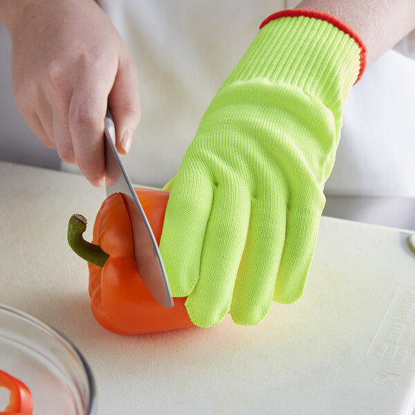 A person wearing yellow Mercer Culinary cut-resistant gloves cutting a bell pepper.