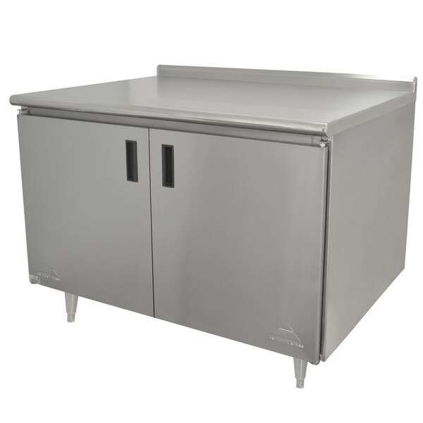 A stainless steel Advance Tabco work table with an enclosed base and hinged doors.