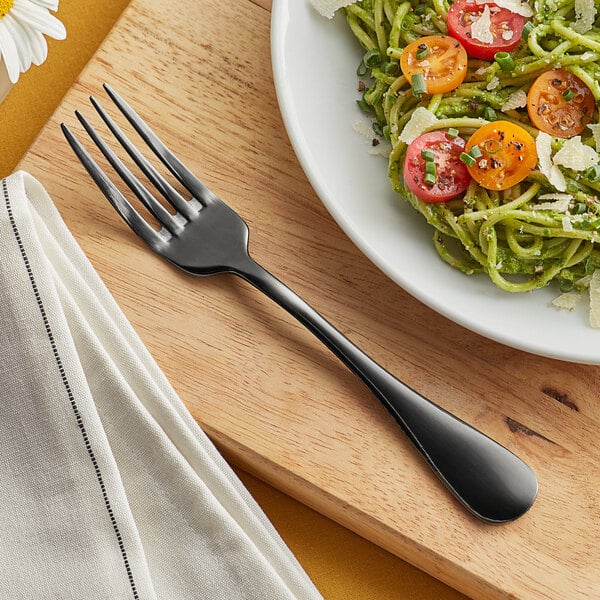 An Acopa Vernon stainless steel dinner fork on a plate of pasta with tomatoes and parmesan cheese.