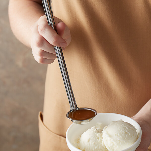 A person using a Vollrath stainless steel ladle to scoop ice cream into a bowl.