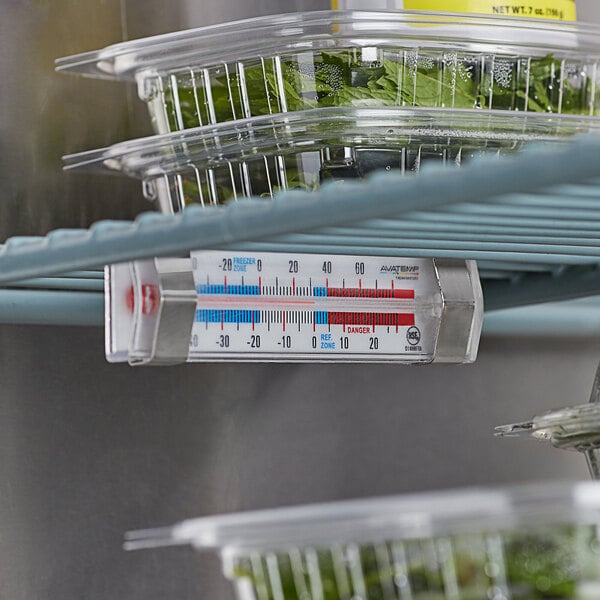 An AvaTemp refrigerator/freezer thermometer on a shelf with food containers.