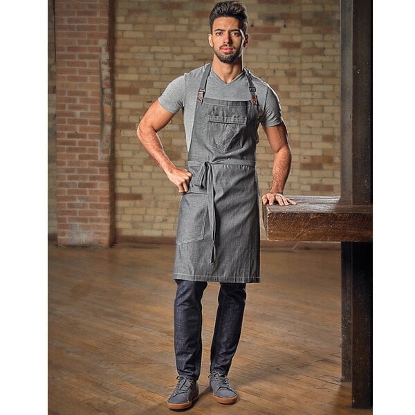 A man wearing a Mercer Culinary denim apron with leather accents.
