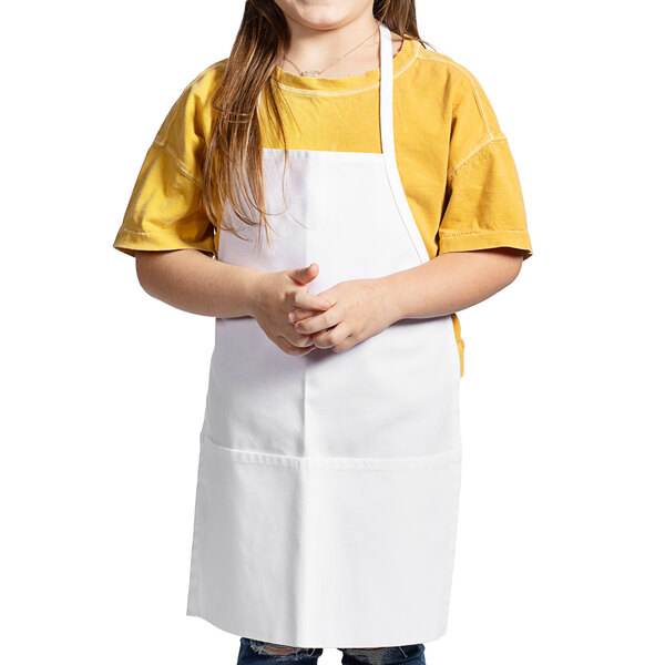 A little girl wearing a white Uncommon Chef child bib apron.