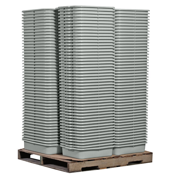 A stack of Tablecraft grey rectangular plastic bus tubs on a wooden pallet.
