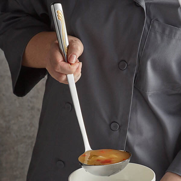 A chef using a Vollrath Windway stainless steel ladle to serve soup.