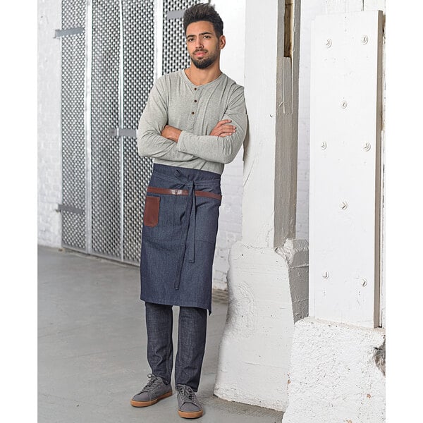 A man wearing a Mercer Culinary indigo denim bistro apron with brown leather details.