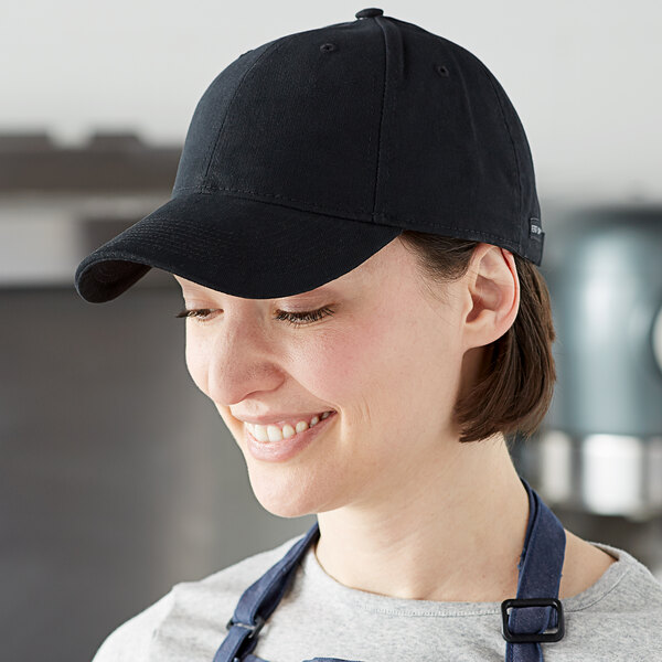 A woman wearing a black Henry Segal cap and apron in a professional kitchen.