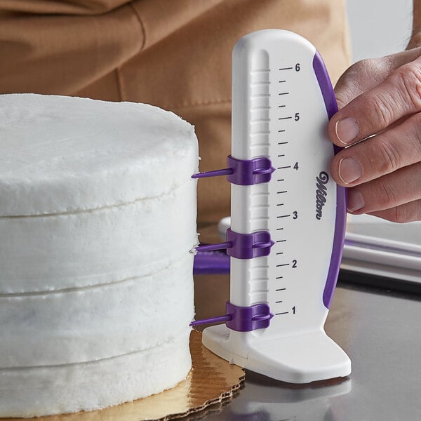 A person using the Wilton adjustable cake marker to cut a cake.