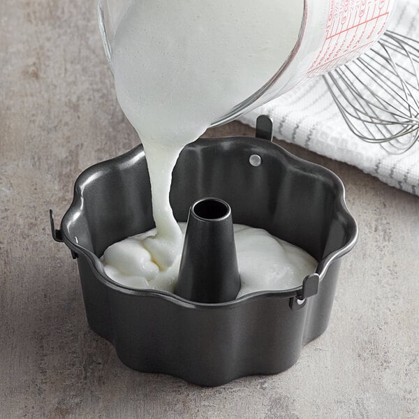 Batter being poured into a Wilton scalloped Bundt cake pan.