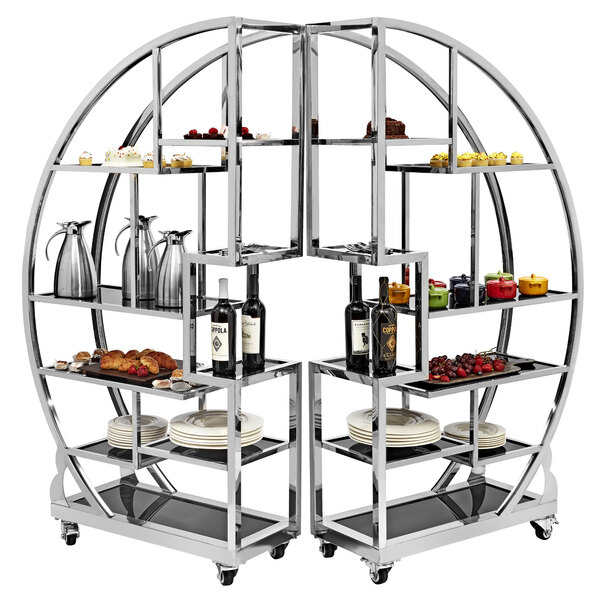 A Bon Chef stainless steel mobile buffet tower with glass shelves holding food and drinks.