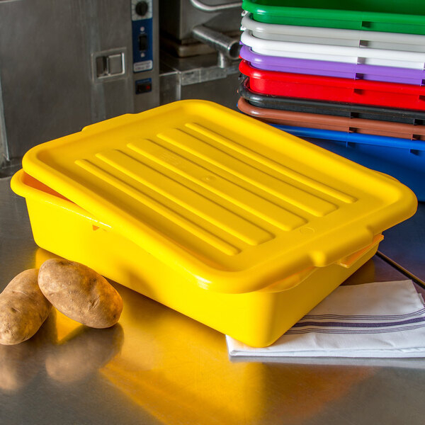 A yellow Carlisle polypropylene lid on a yellow plastic container with potatoes.