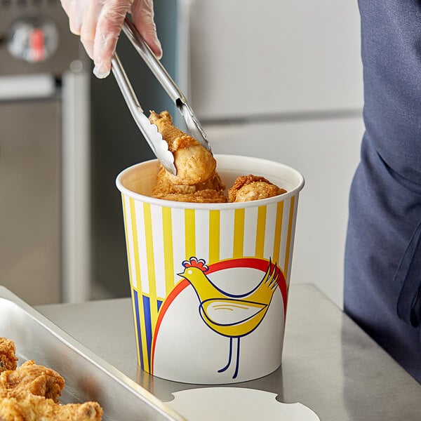 A person using metal tongs to grab food from a Choice chicken bucket.