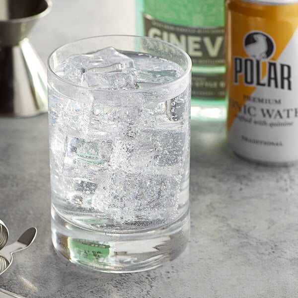 A glass of ice with a can of Polar tonic water on a table.