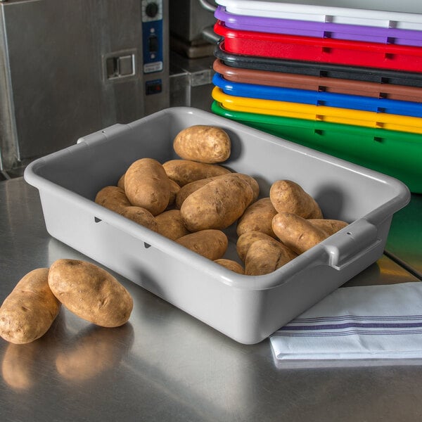 A gray Carlisle bus tub filled with potatoes on a counter.