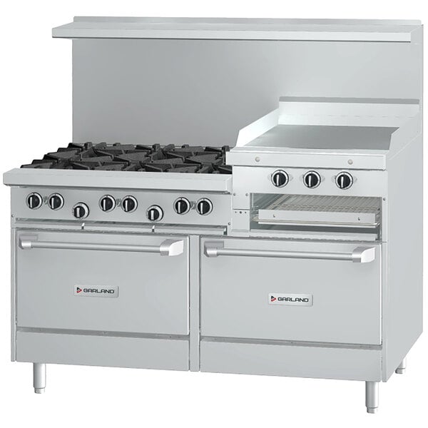 A white Garland commercial range with 6 burners, a raised griddle, and 2 ovens, with black knobs.