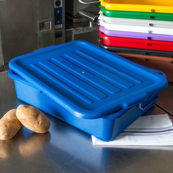 A blue plastic Carlisle bus tub with a lid holding a stack of potatoes.