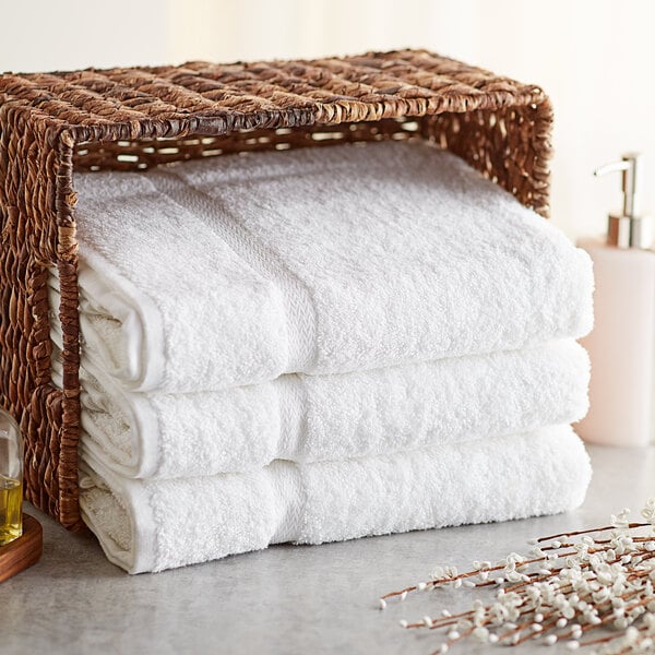 A basket with a stack of white Lavex bath towels.