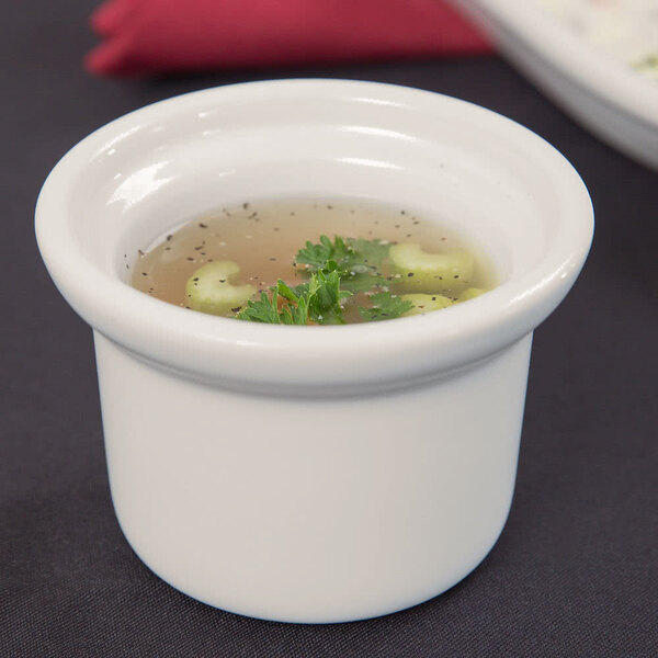A Tuxton eggshell white soup crock filled with soup and greens.