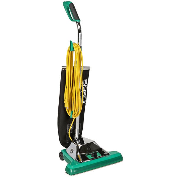 A Bissell Commercial ProShake bagged upright vacuum cleaner with a yellow handle and cord.