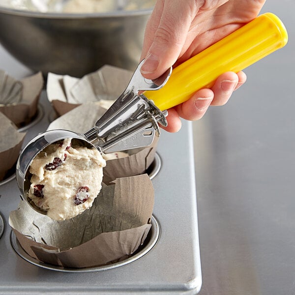 A person using a Hamilton Beach yellow thumb press disher to scoop food.