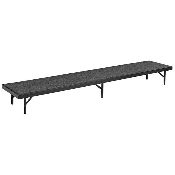 A gray rectangular carpeted stage riser with metal legs.