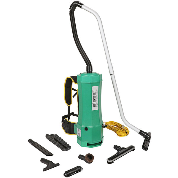 A green Bissell Commercial backpack vacuum cleaner with a yellow cord and various tools.