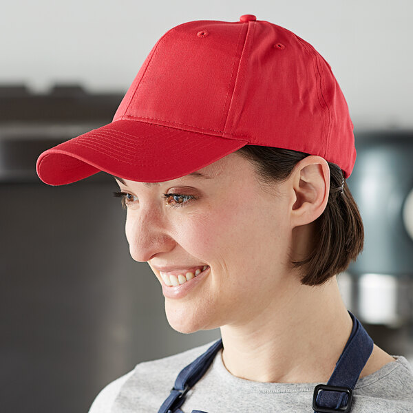 A woman wearing a red Mercer Culinary baseball cap in a professional kitchen.