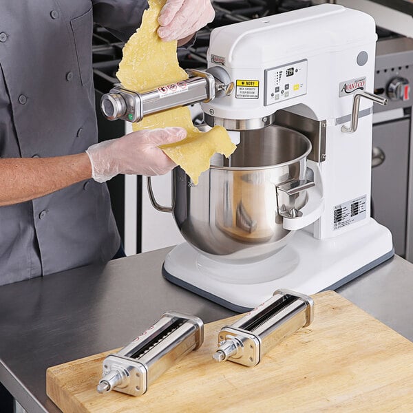 A man using an Avantco pasta roller and cutter attachment to make pasta with a mixer.