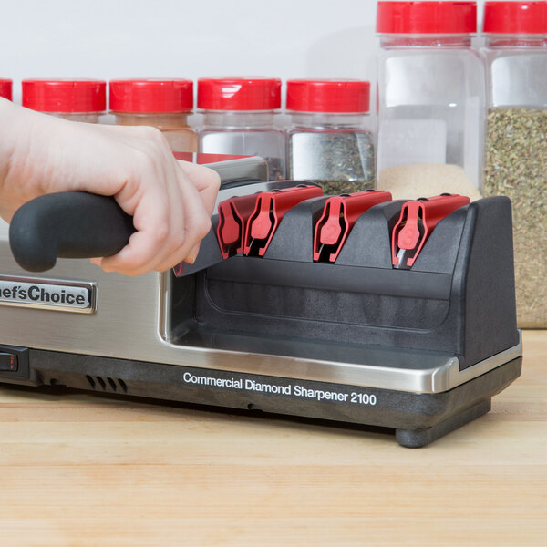 A hand inserting a knife into the Edgecraft Chef's Choice 3 Stage Asian Style Knife Sharpener Module.