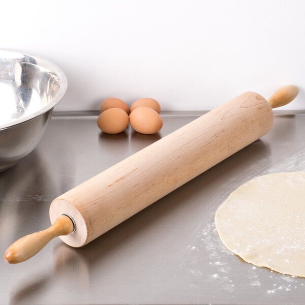 An Ateco maple wood rolling pin on a counter with dough.